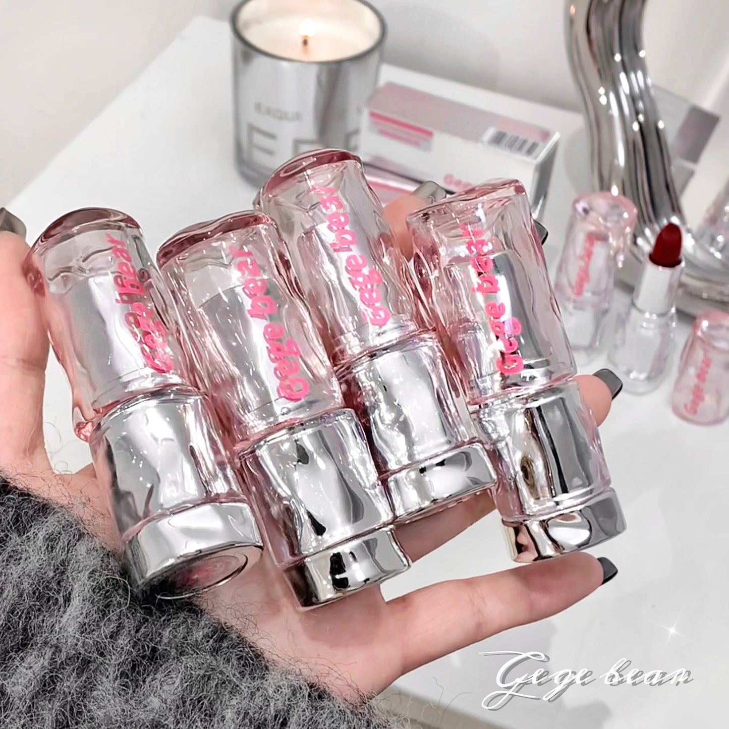 Hand holding multiple lip glosses with a blurred background