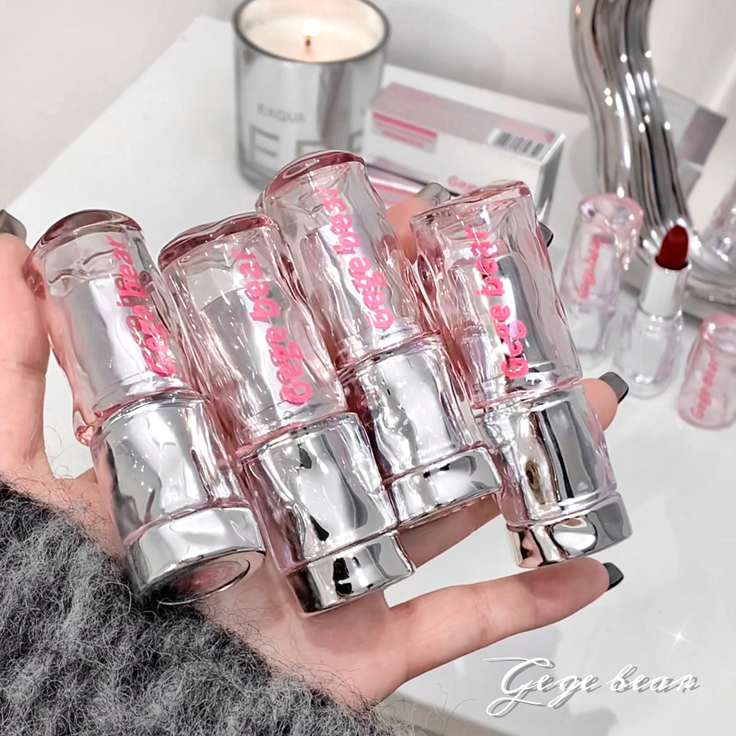 Hand holding multiple lip glosses with a blurred background