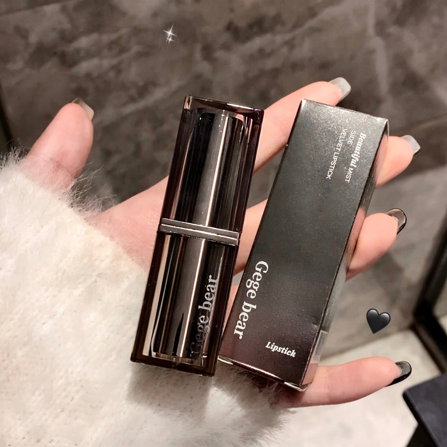 Lipstick with case held by a hand on a textured surface