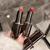 Three lipsticks from the brand 'Age Bear' held by a hand against a neutral background.