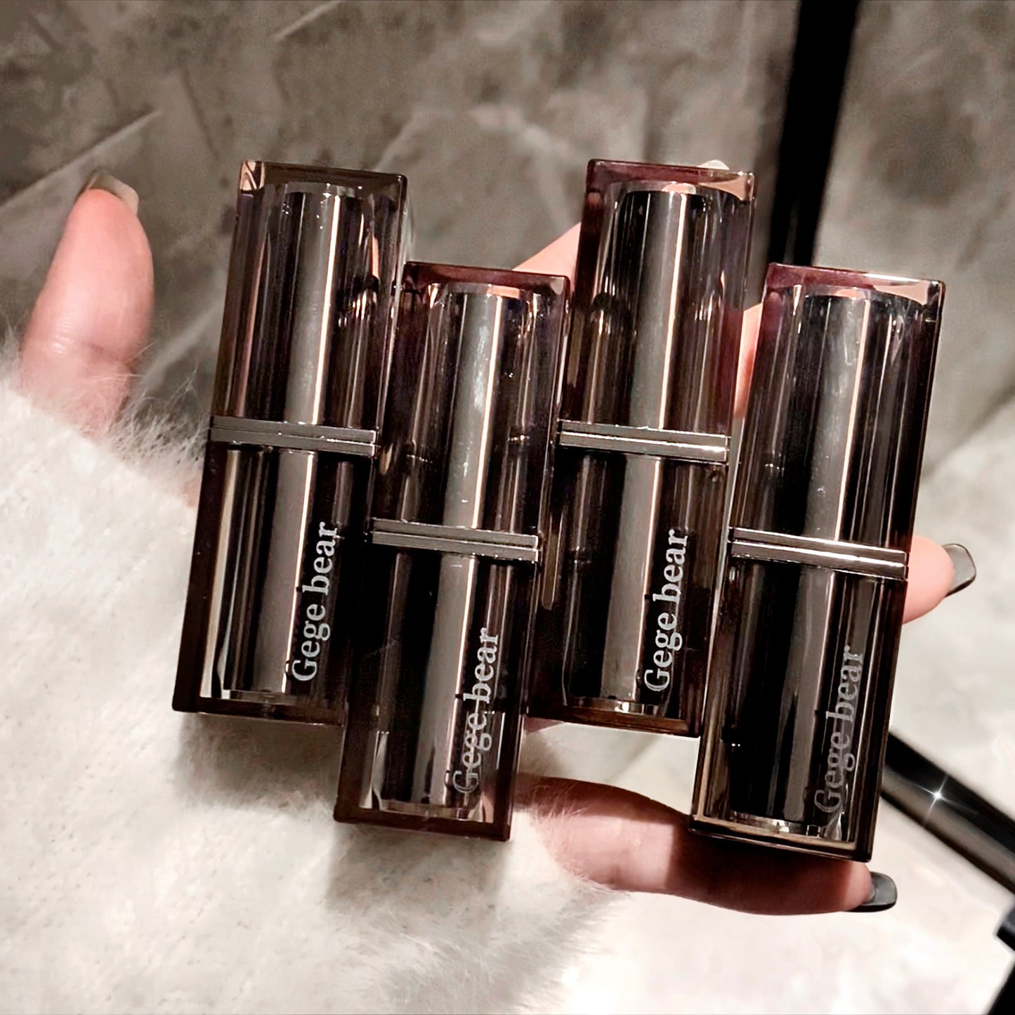 Four Gege bear lipsticks held in a hand against a neutral background