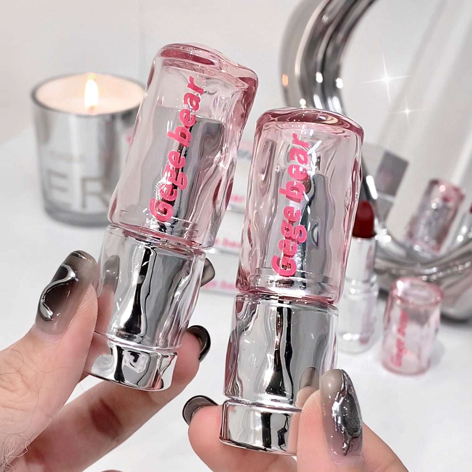 Two Gige bear lip glosses held by a hand with a blurred background