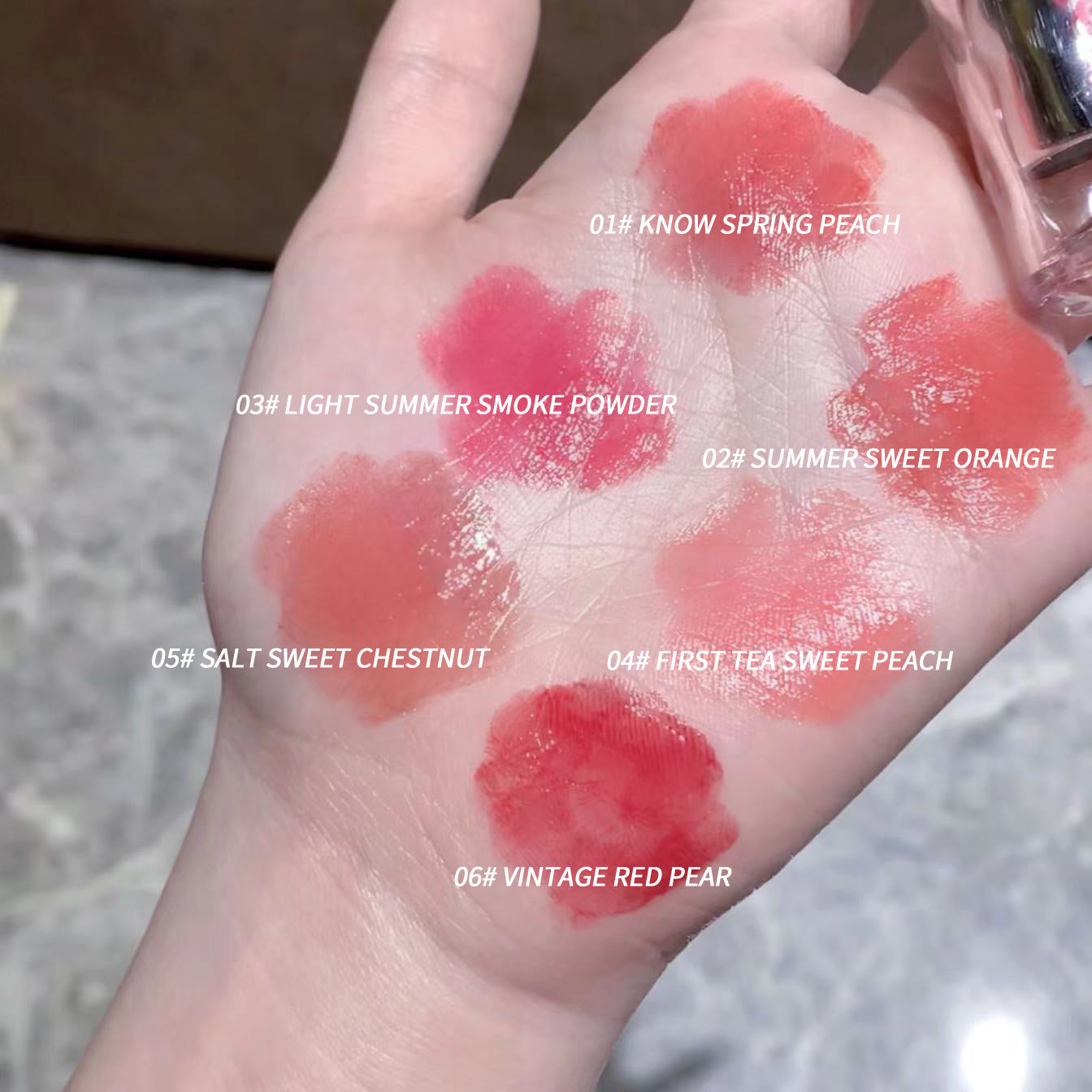 Hand with lipstick swatches labeled with color names on a blurred background