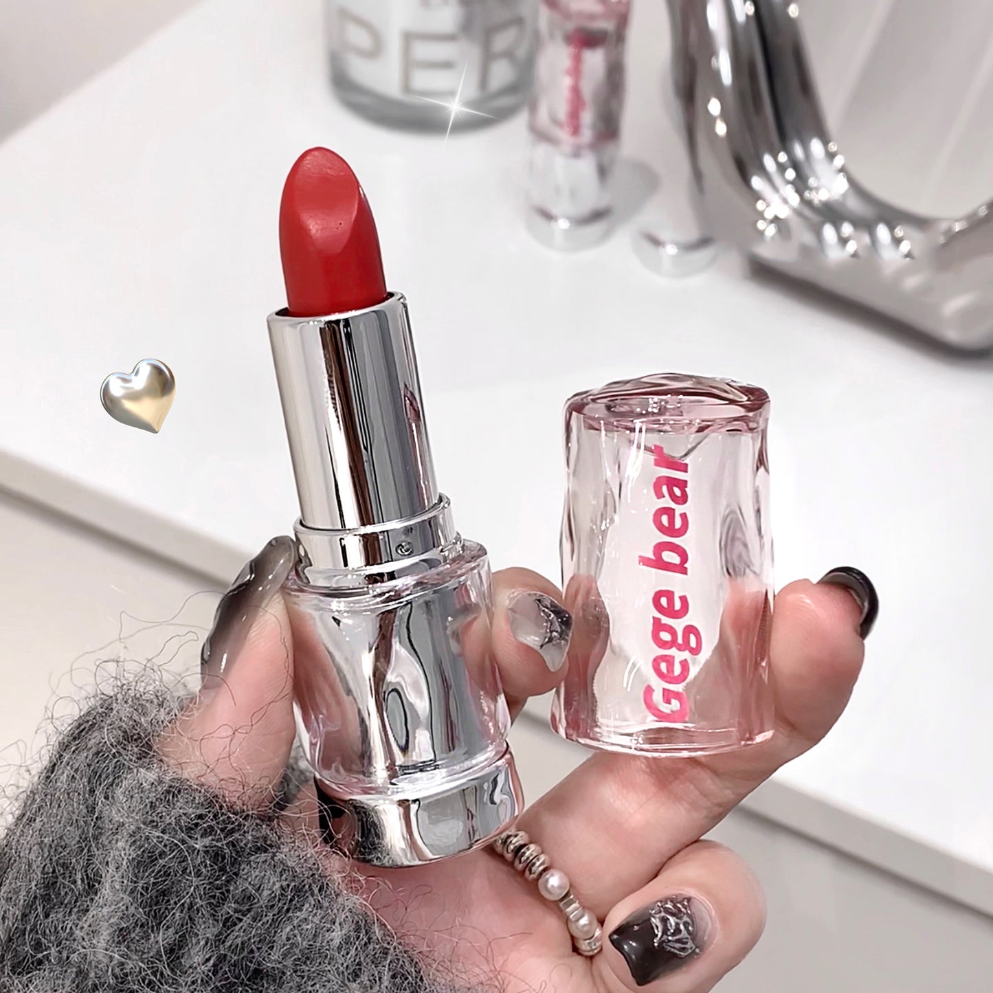 Red lipstick held by a hand with 'Gegebear' branding visible