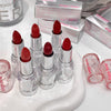 Red lipsticks with clear casings on a white surface, surrounded by 'Gee Bear' boxes.