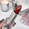 Red lipstick held by a hand with a blurred background