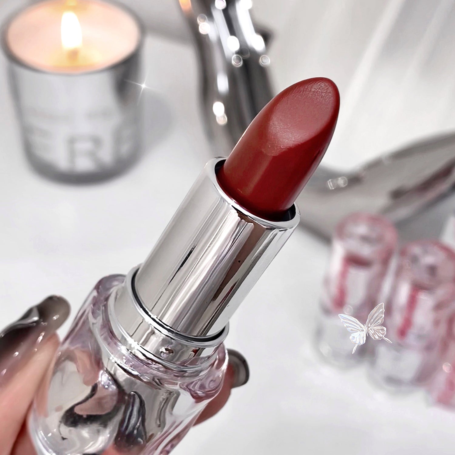 Red lipstick held by a hand with a blurred background