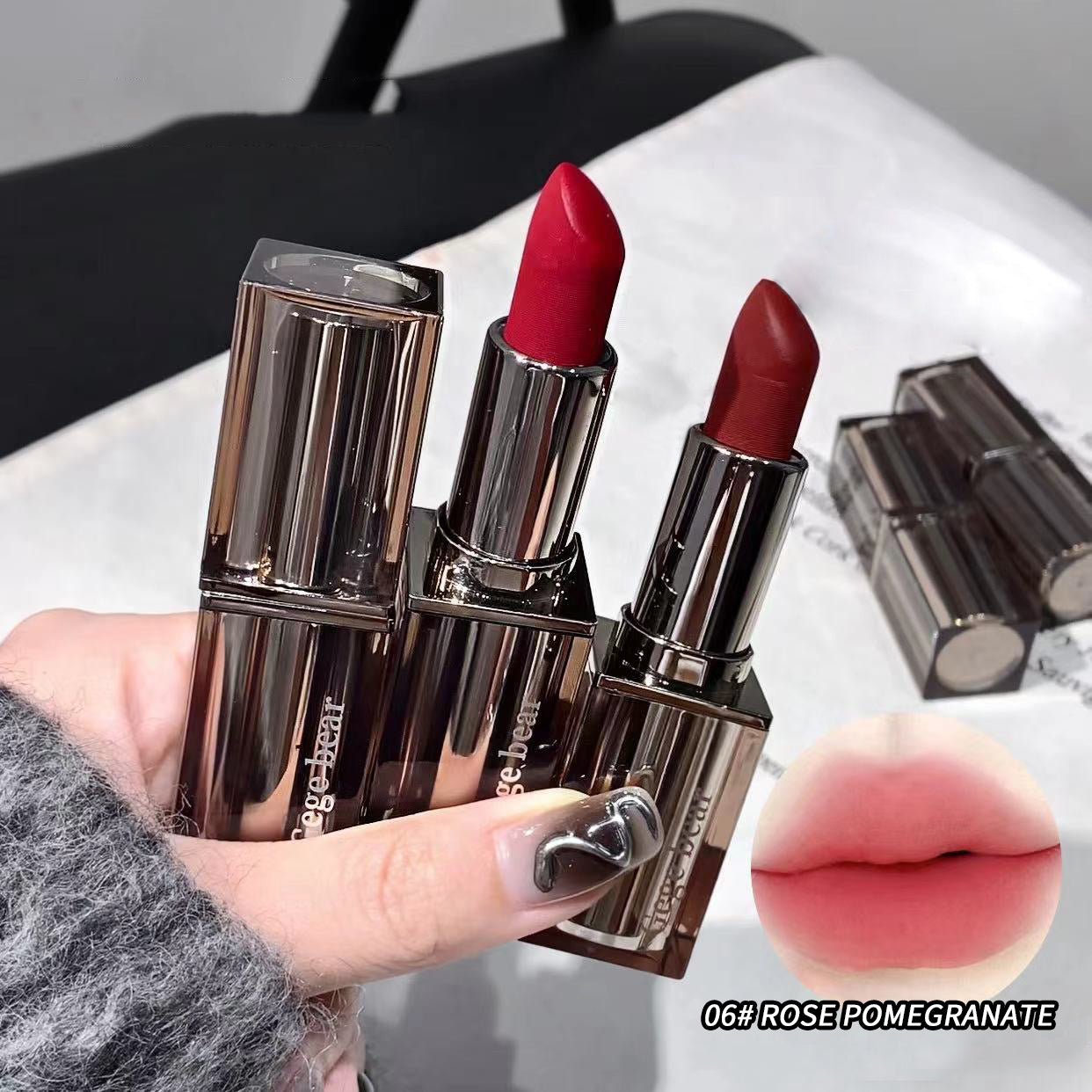 Three red lipsticks with brown cases held by a hand, with an inset of lips wearing the lipstick color.