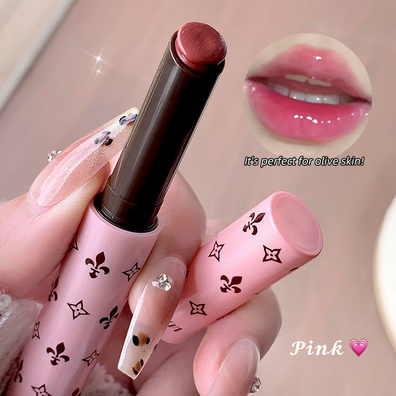 Pink lipstick with decorative packaging held by a hand, close-up with lip swatch.