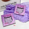 Two boxes of false eyelashes with a purple crumpled paper background