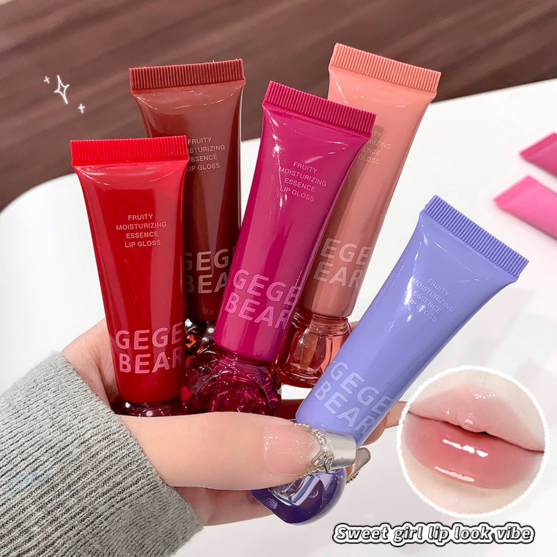 Hand holding multiple GEGER BEAR lip gloss tubes with a close-up of glossy lips.
