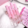 Pink lip gloss tubes with clear caps held by a hand, with pink boxes in the background.