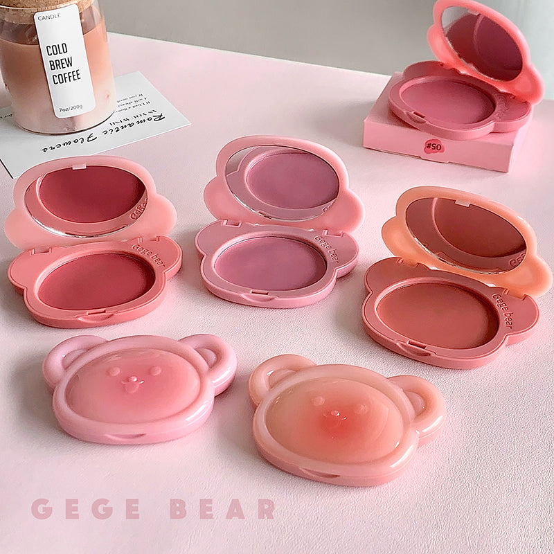 Set of pink makeup products with bear-shaped cases on a light surface, featuring the brand 'GEGE BEAR'.