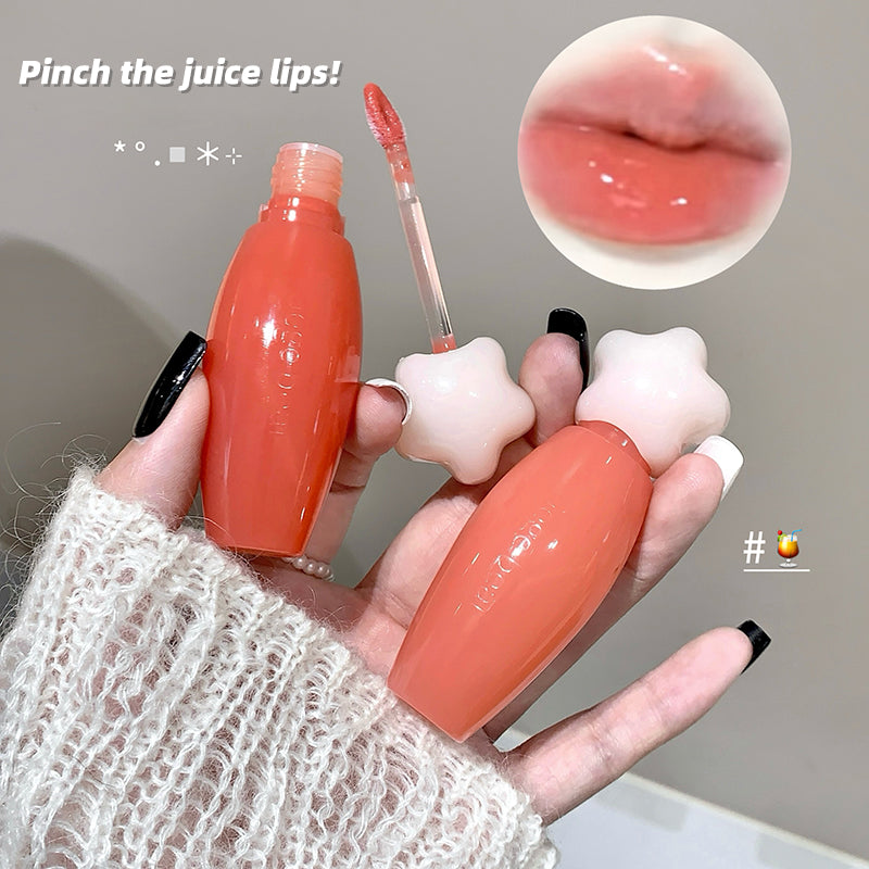 Lip gloss with star-shaped applicator held by a hand, close-up of glossy lips shown.