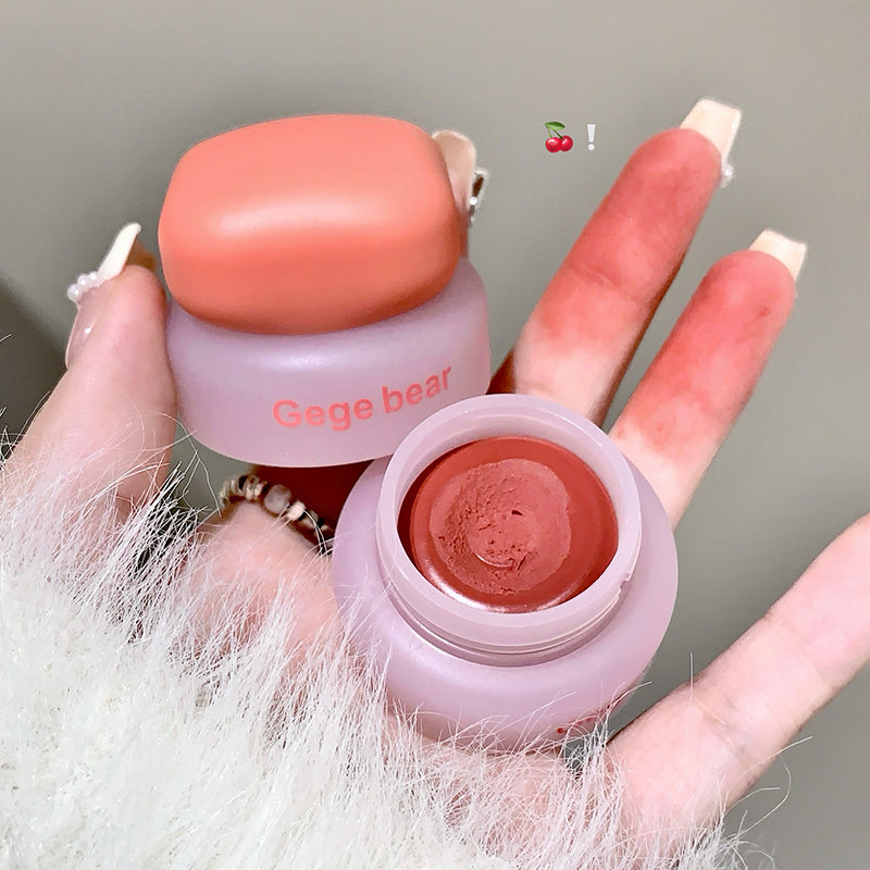 Small pink container with a cosmetic product, held by a hand with painted nails.