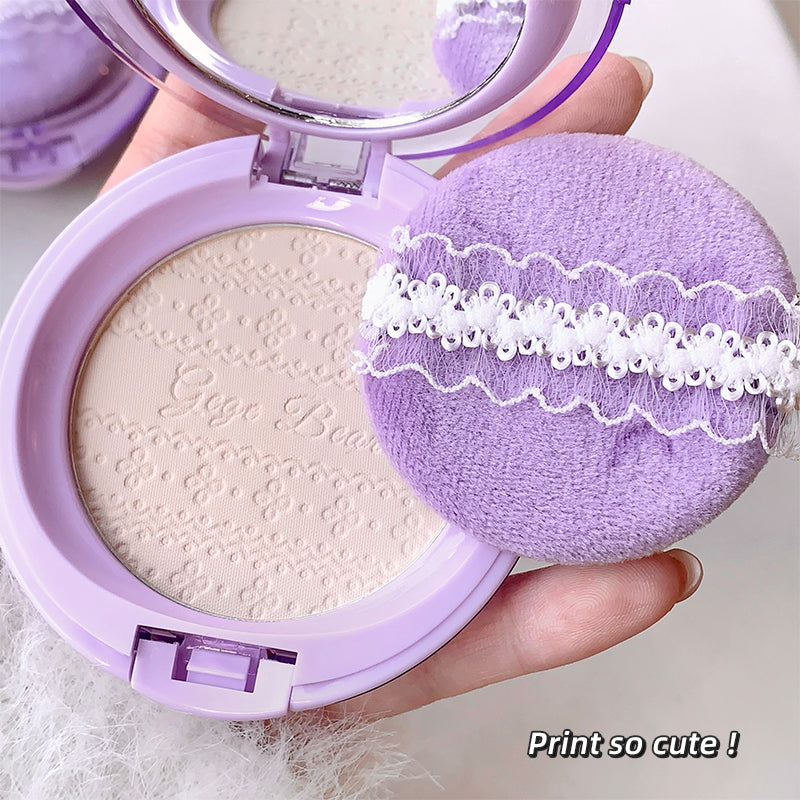 Makeup compact with purple lid and matching sponge, held by a hand.