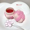 Pink and white cosmetic container with a spoon and paw-shaped lid on a heart-shaped base.