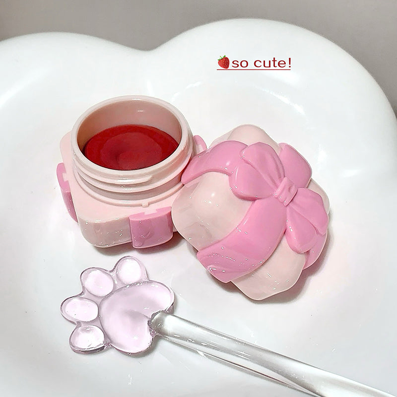 Pink and white cosmetic container with a spoon and paw-shaped lid on a heart-shaped base.