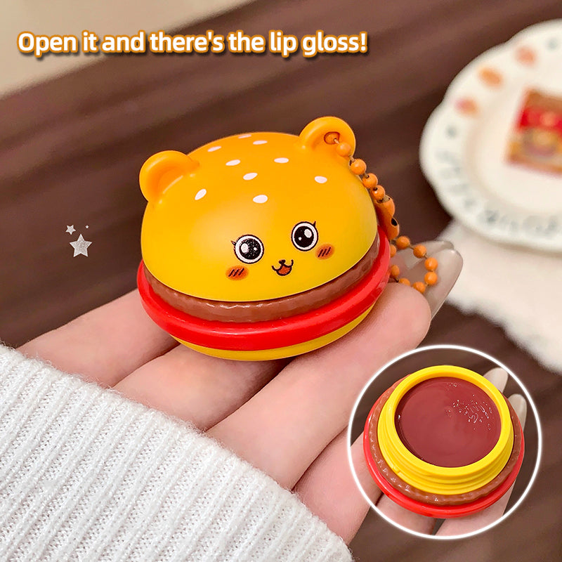 Yellow lip gloss case with bear design held by a hand, showing the product inside.