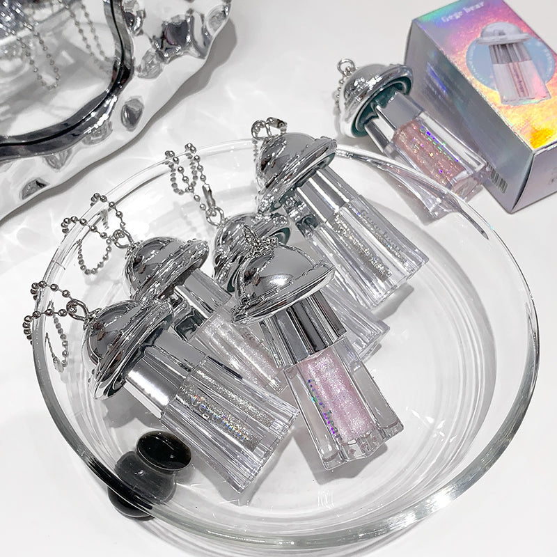 Silver glittery lip gloss with a necklace on a white surface