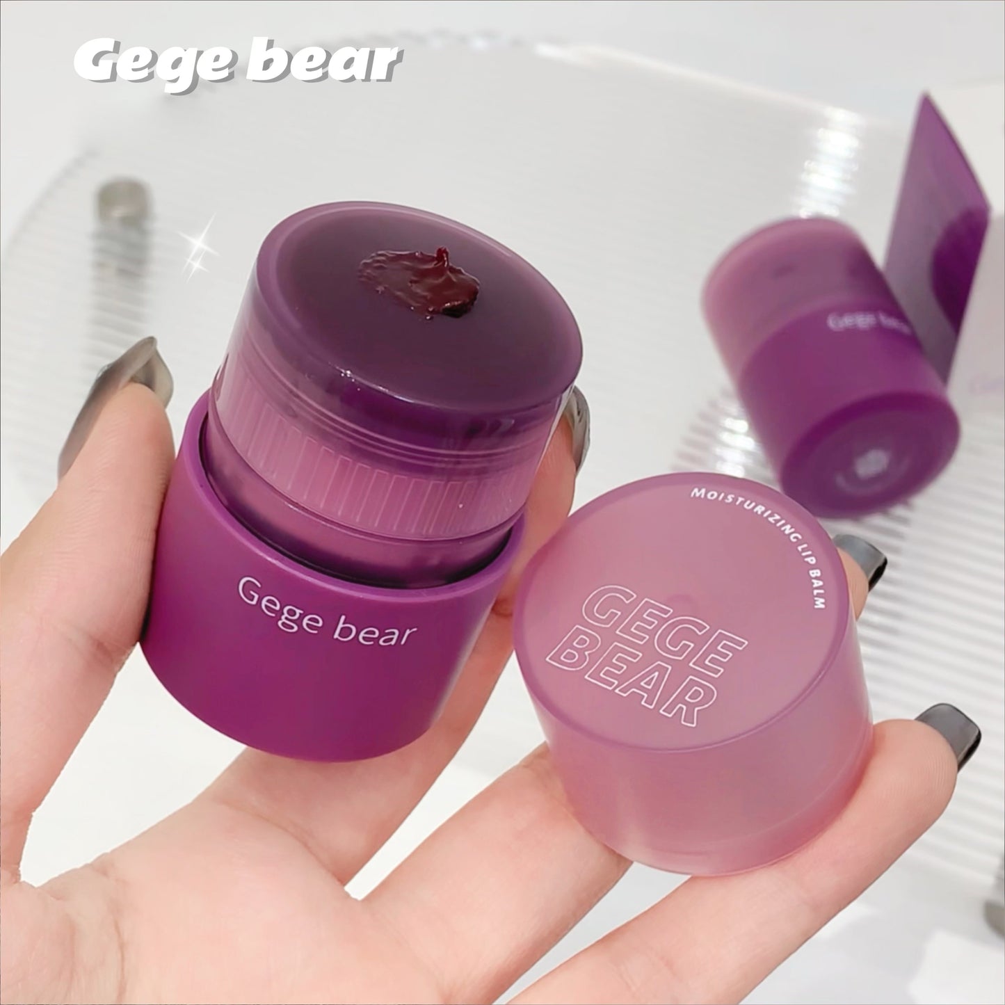 Purple Gege Bear lip balm container held in a hand with a white background