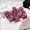 Hand holding six red lip glosses with 'Gotta' branding on a white background