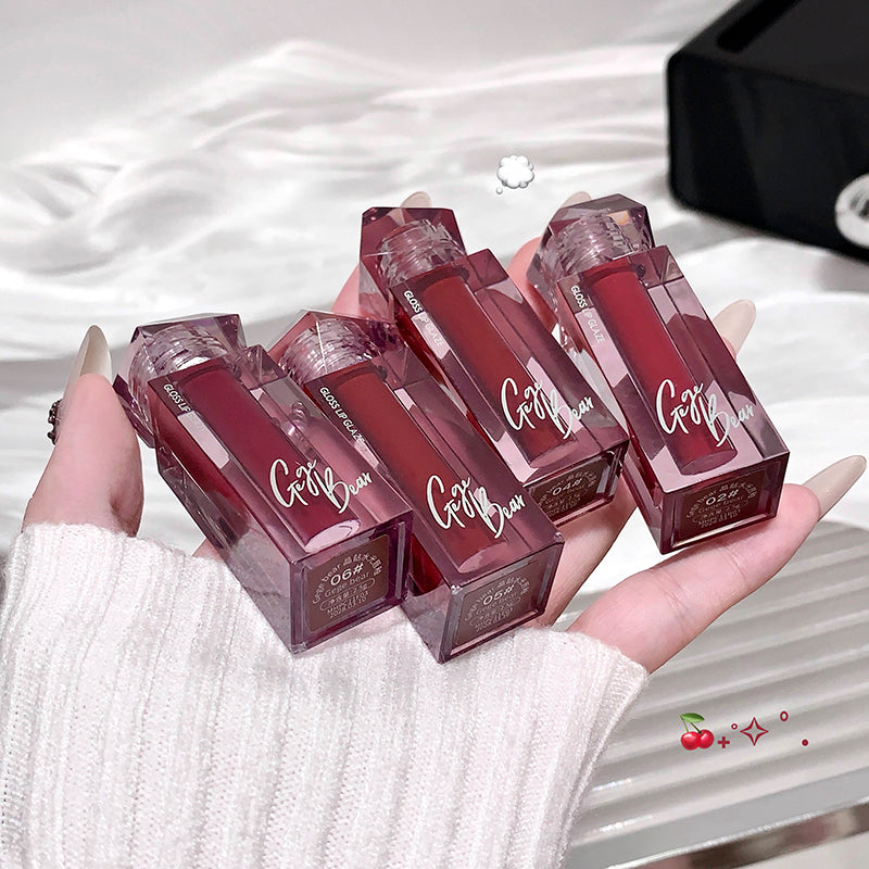 Hand holding six red lip glosses with 'Gotta' branding on a white background