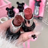 Two lipsticks with paw-shaped caps held by a hand against a blurred background.