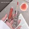 Lip gloss with applicator held in hand, close-up of product, and swatch on a surface.