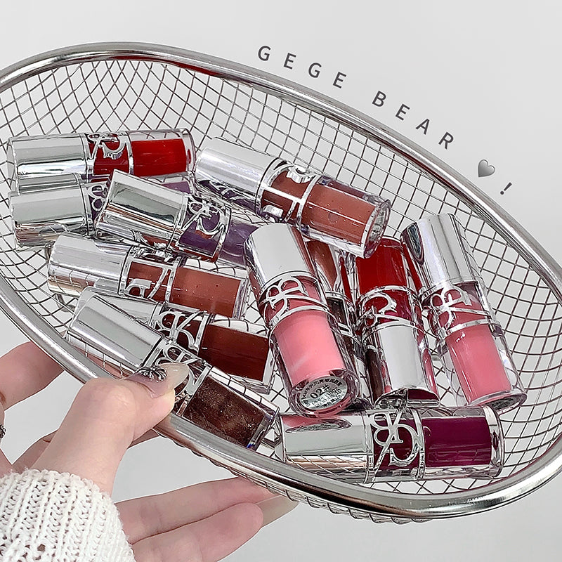 Collection of lip glosses on a decorative tray with 'GEGE BEAR' branding.