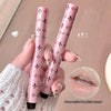 Two pink lip glosses with decorative patterns held by a hand, with a close-up of lips wearing the product.