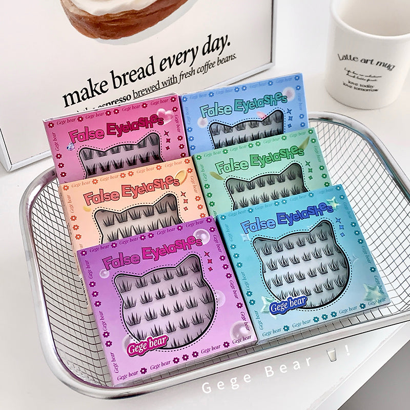 Colorful boxes of false eyelashes on a metal tray with a coffee mug and bread in the background.