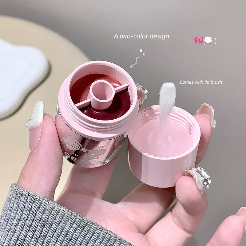 Pink lip balm with a brush held by a hand, on a neutral background