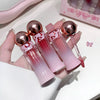 Set of pink and red gradient lip glosses with rose gold caps held by a hand.