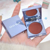 Compact blush with 'GEGE BEAR' branding held in a hand against a blurred background.