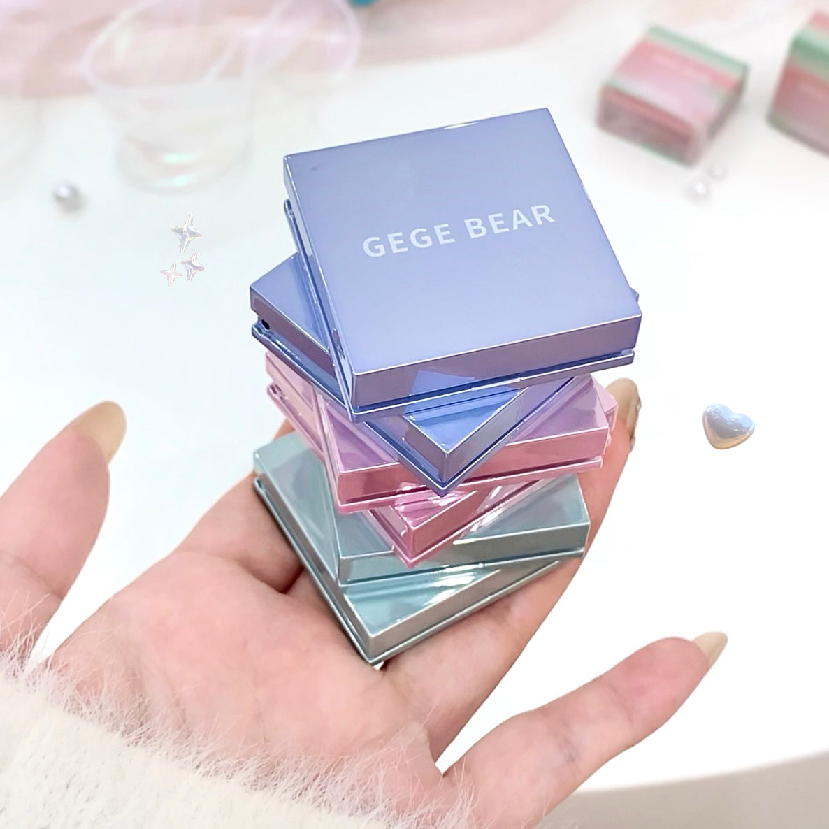Stack of GEGE BEAR product boxes held in a hand with a soft focus background