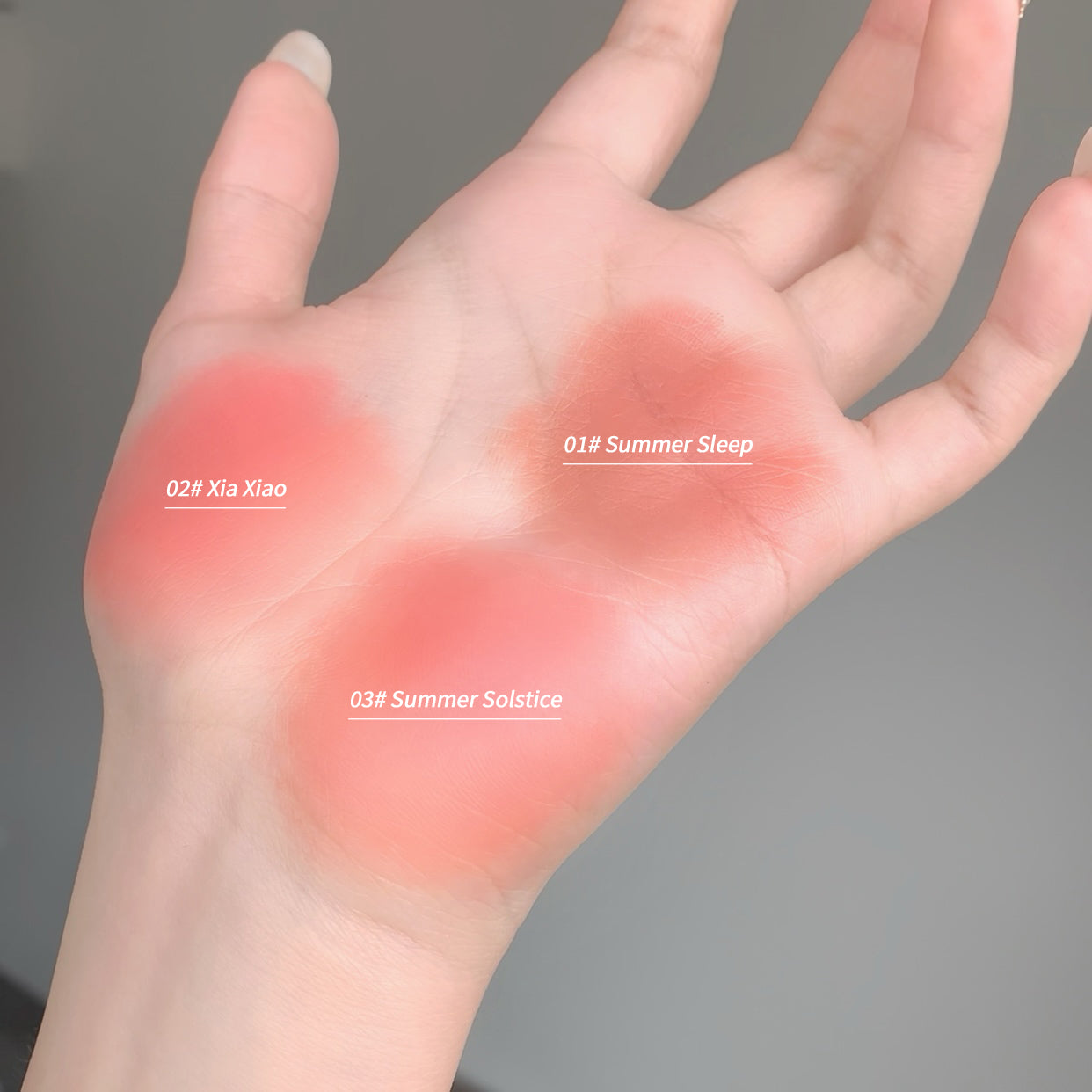 Hand with three colored blush swatches labeled '02# Xia Xiao', '01# Summer Sleep', and '03# Summer Solstice' on a gray background.