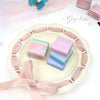 Pastel-colored boxes with 'Geze bear' branding on a decorative plate with ribbons.