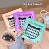 False eyelashes packaging with a hand holding one, on a wooden surface.