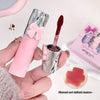 Pink lip gloss with silver cap held by a hand, close-up on a light background.