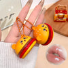 Hamburger-shaped keychain held in a hand with a close-up of lips in the corner.