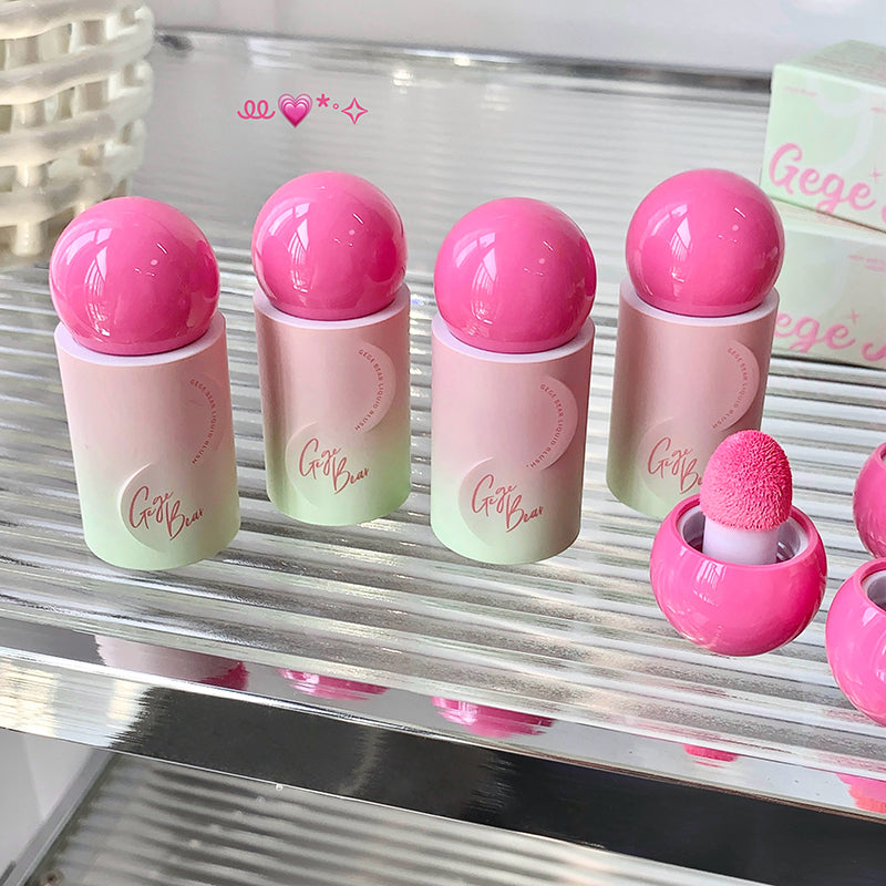 Set of pink and green makeup products with spherical caps on a reflective surface.