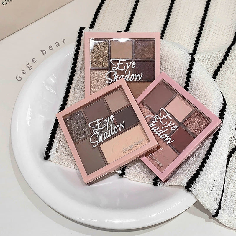 Three eye shadow palettes on a white plate with a striped fabric background