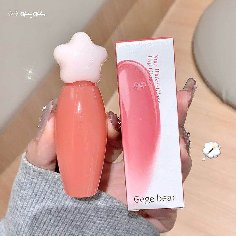 Star-shaped lip gloss with packaging held by a hand on a neutral background