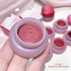 Pink lip balm container held by a hand with more lip balms in the background.