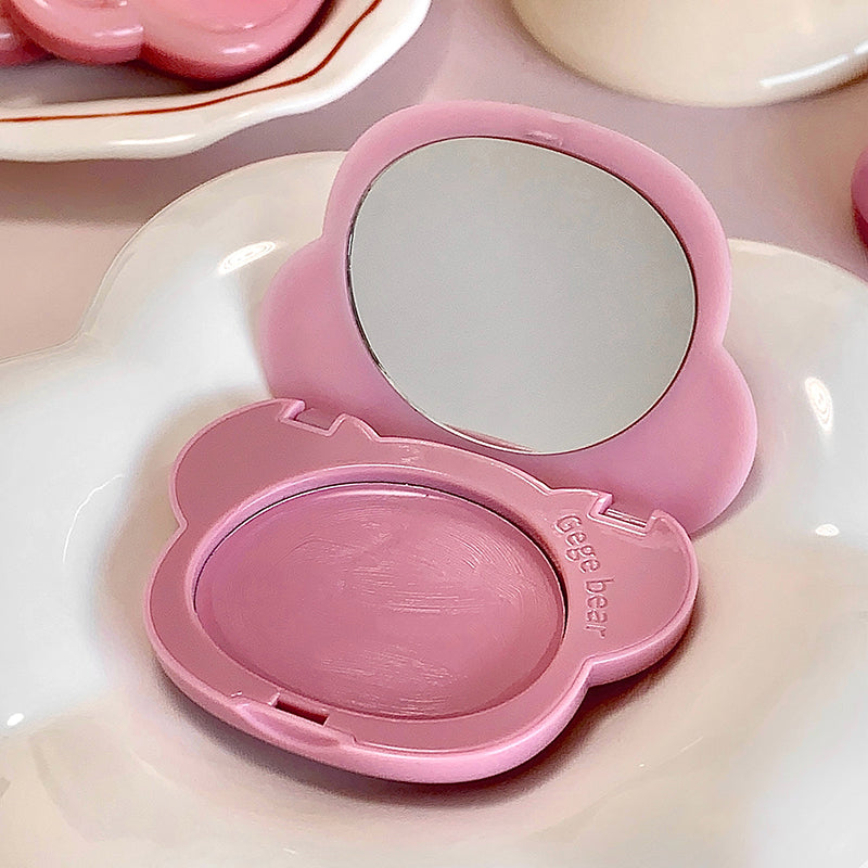 Pink makeup compact with mirror on a white surface