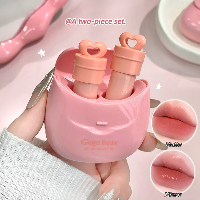Pink two-piece cosmetic set with heart-shaped caps, held by a hand.