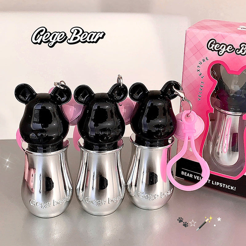 Three metallic bear-shaped lipsticks with a pink box labeled 'Gege Bear' on a reflective surface.