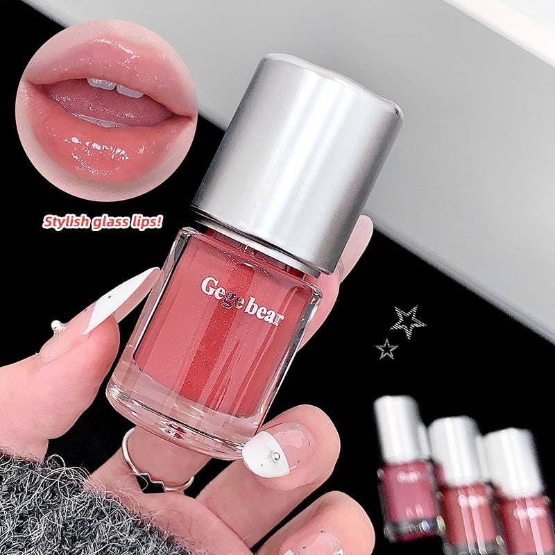 Hand holding a bottle of 'Geebear' nail polish with a close-up of glossy lips and additional bottles in the background.