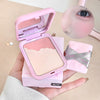 Pink makeup compact held in a hand with a blurred eye and brush in the background